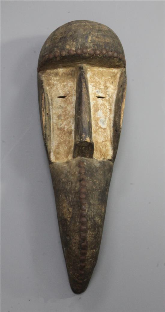 A carved wood bird beak mask, with iron studded and whitened decoration, 45cm